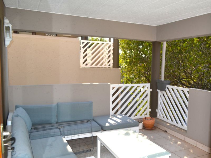 A covered balcony featuring tiled flooring and white lattice balustrades, providing a functional outdoor living space.