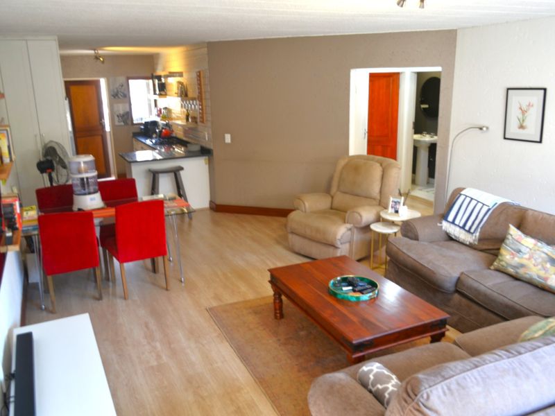 Open-plan living and dining area featuring laminate flooring and an integrated kitchen space with built-in cabinetry and countertops.