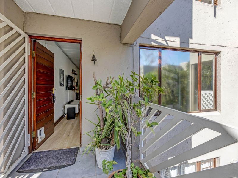 Entrance area featuring a solid wood front door, security gate, and tiled flooring, providing access to the apartment interior.