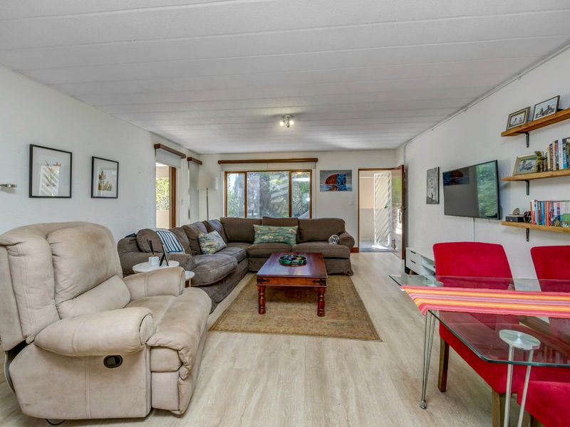 Spacious open-plan living and dining area featuring light-toned laminate flooring, neutral walls, and large windows providing natural light.