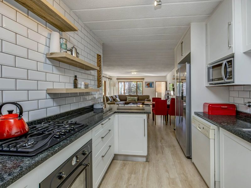 Modern open-plan kitchen featuring granite countertops, subway tile backsplash, and integrated appliances, flowing seamlessly into the adjacent dining and living area.