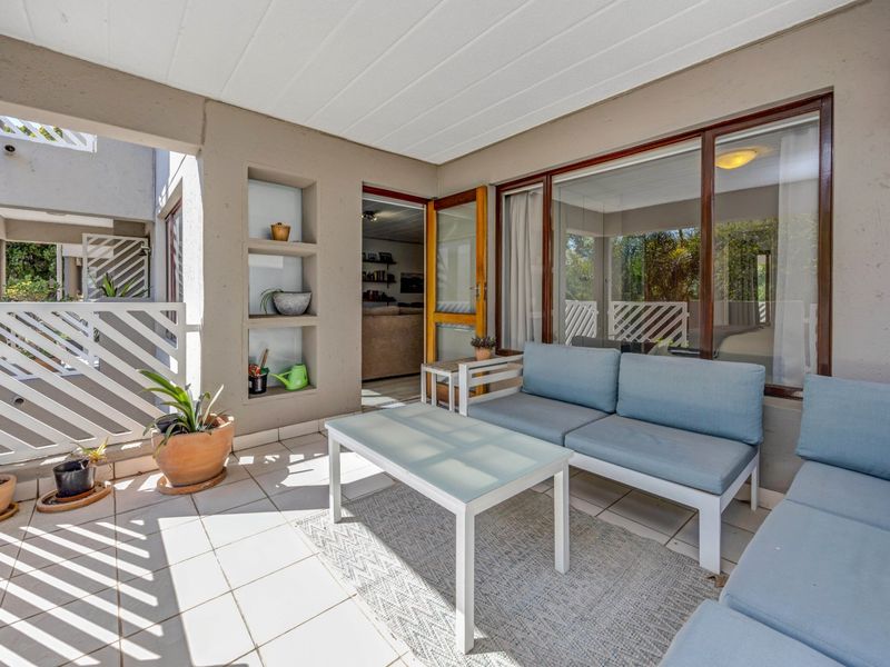 A covered patio area featuring tiled flooring, built-in wall niches, and direct access to the interior living space through a sliding glass door.