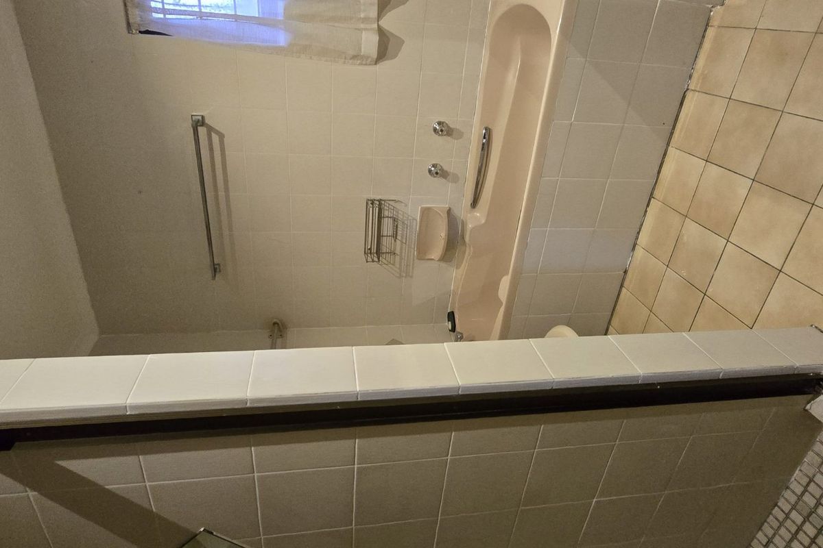 A dated bathroom featuring a bathtub, separate shower enclosure, and tiled finishes, offering potential for a modern renovation.