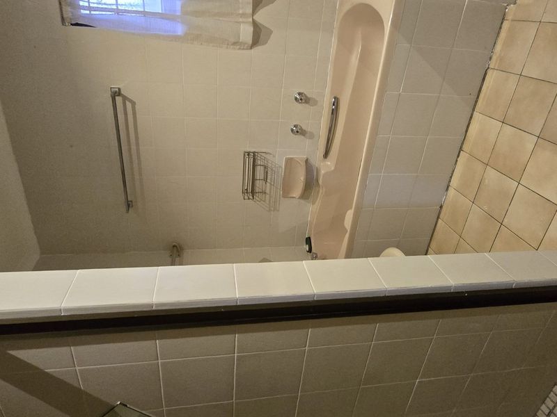 A dated bathroom featuring a bathtub, separate shower enclosure, and tiled finishes, offering potential for a modern renovation.