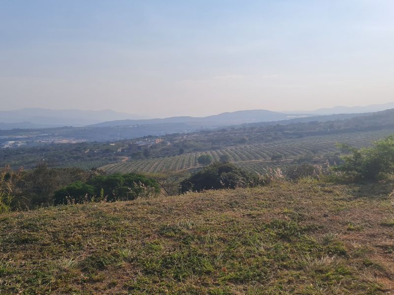 Expansive elevated landscape view overlooking rolling hills, agricultural fields, and distant mountain ranges.