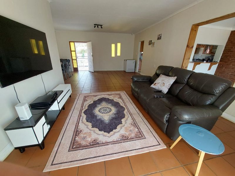 Spacious living area featuring terracotta-style tiled flooring, a pass-through window to the kitchen, and direct access to the front entrance.