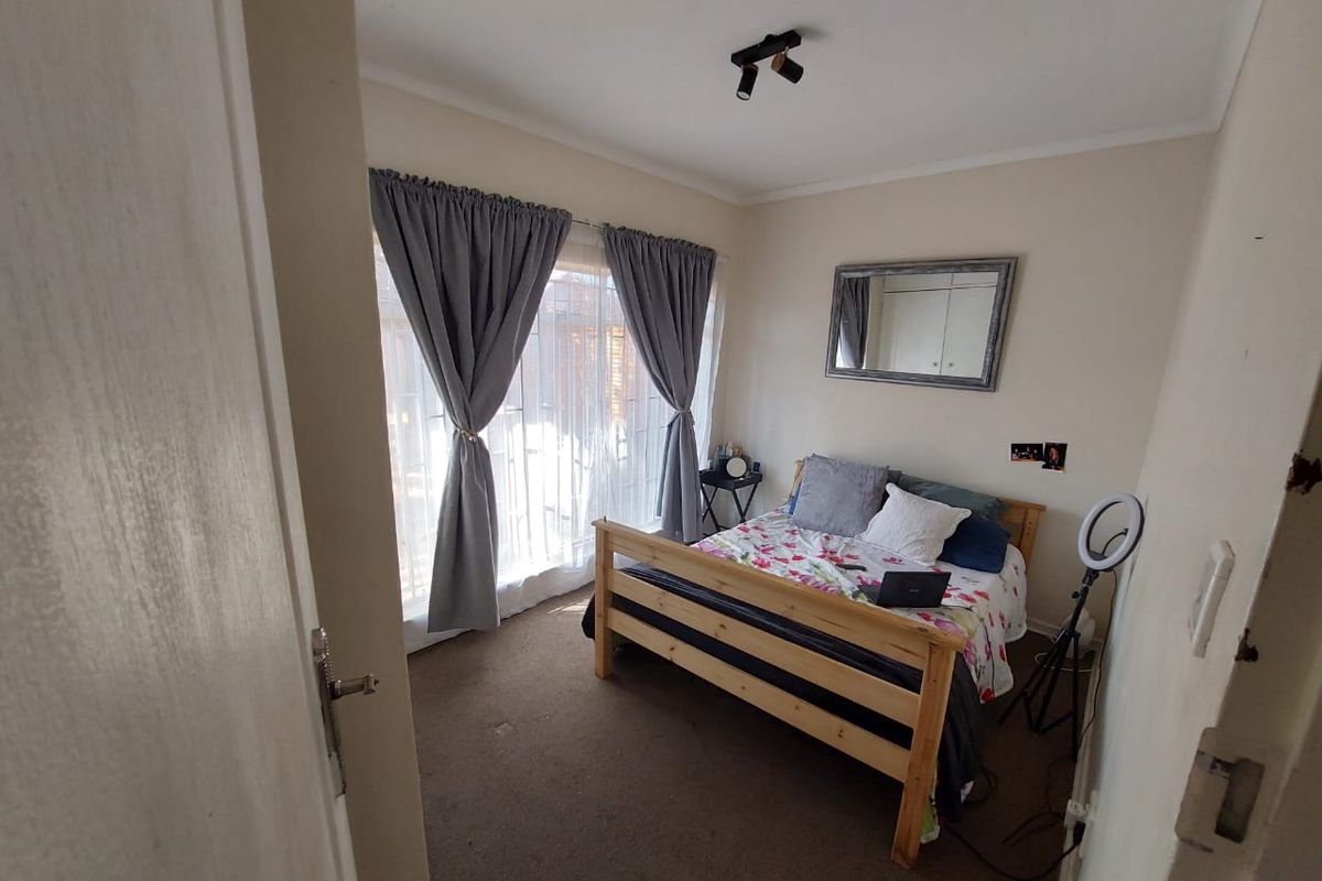 A functional bedroom featuring carpeted flooring, a ceiling-mounted spotlight, and a sliding door providing access to the exterior.
