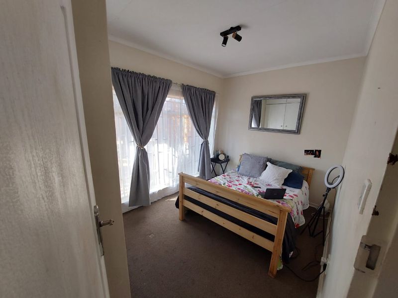 A functional bedroom featuring carpeted flooring, a ceiling-mounted spotlight, and a sliding door providing access to the exterior.