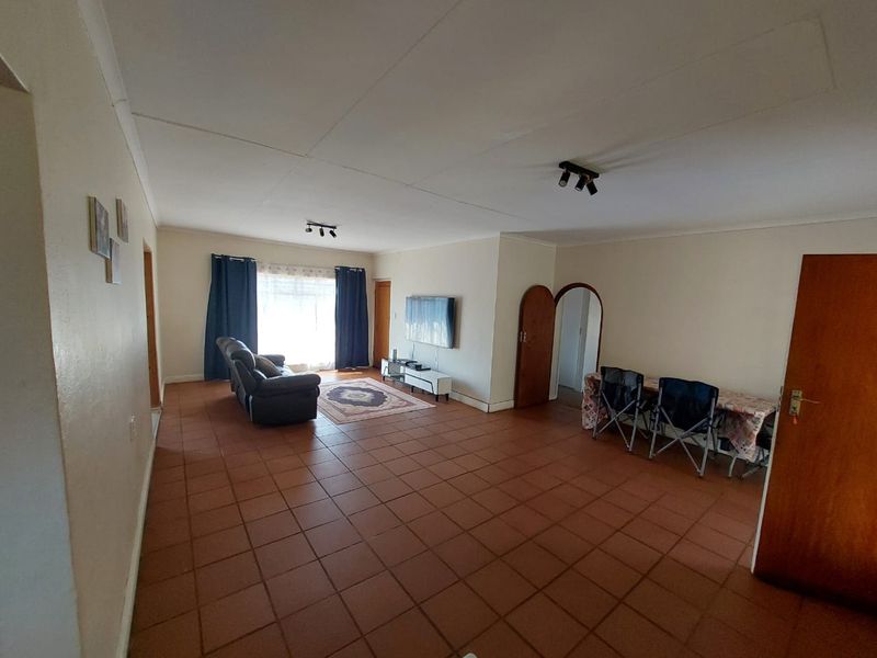 Spacious living area featuring terracotta floor tiles, coved ceilings, and an arched doorway, offering a functional layout with potential for modernization.