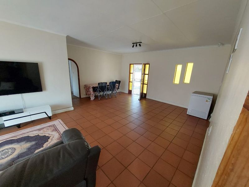 Spacious living area featuring terracotta floor tiles, an arched doorway, and direct access to the exterior via a security gate.