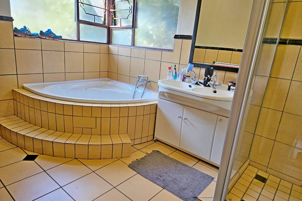 A functional bathroom featuring a corner bathtub, double vanity, and a separate shower enclosure with tiled finishes throughout.