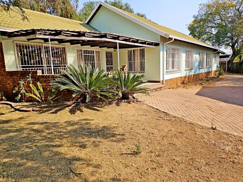 Front view of a single-story house featuring a tiled roof, brick base, and a paved driveway with security bars on the windows.