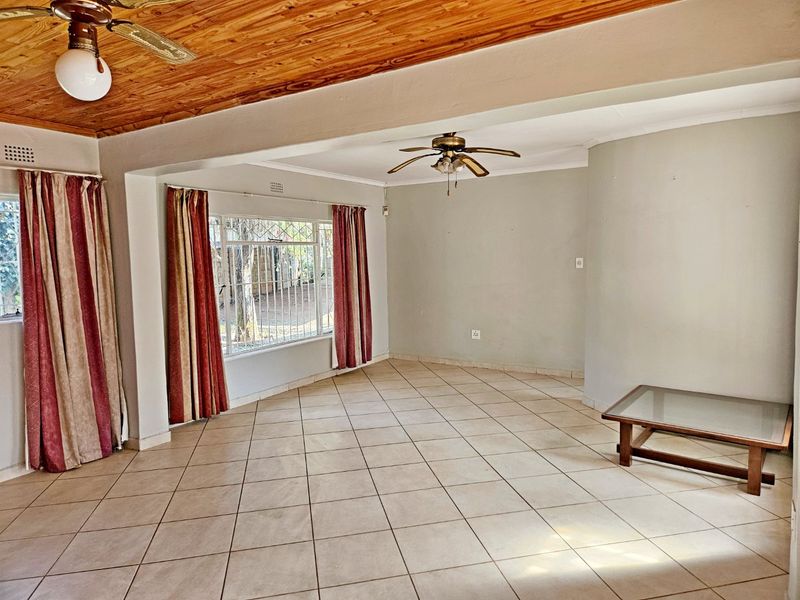 Spacious living area featuring tiled flooring, a timber-paneled ceiling, and dual ceiling fans, offering a blank canvas for interior design.