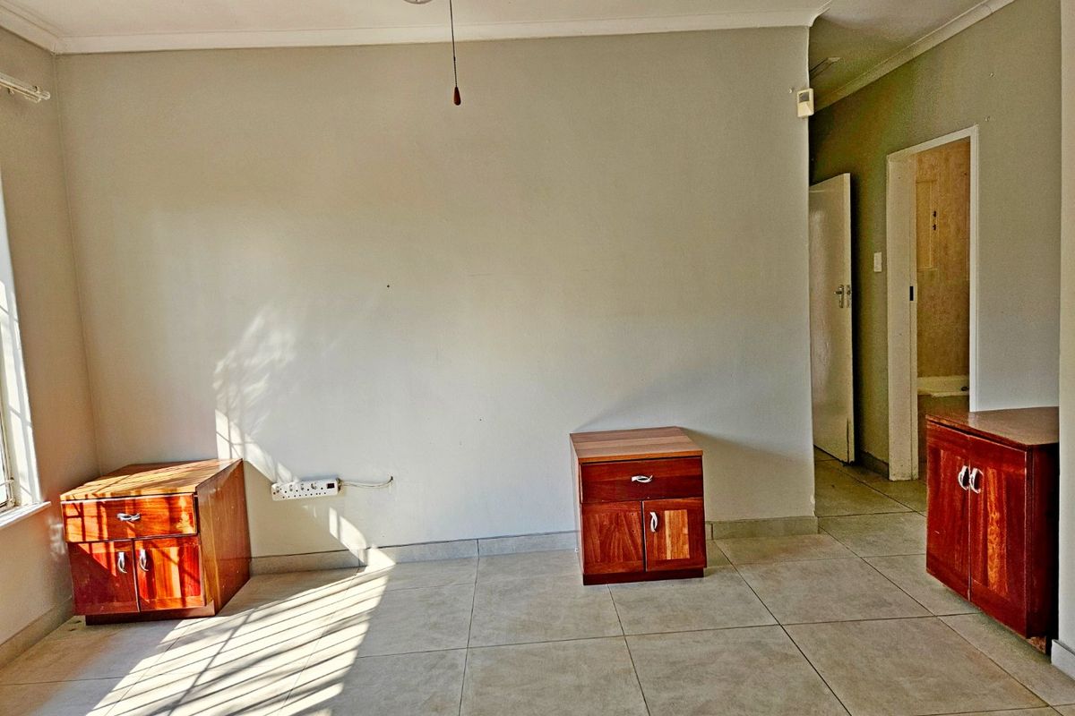 A bedroom featuring tiled flooring, coved ceilings, and neutral wall finishes, providing a functional space with direct access to an adjacent room.