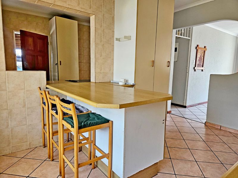 Kitchen area featuring a breakfast bar, tiled flooring, and built-in cabinetry with a neutral finish.