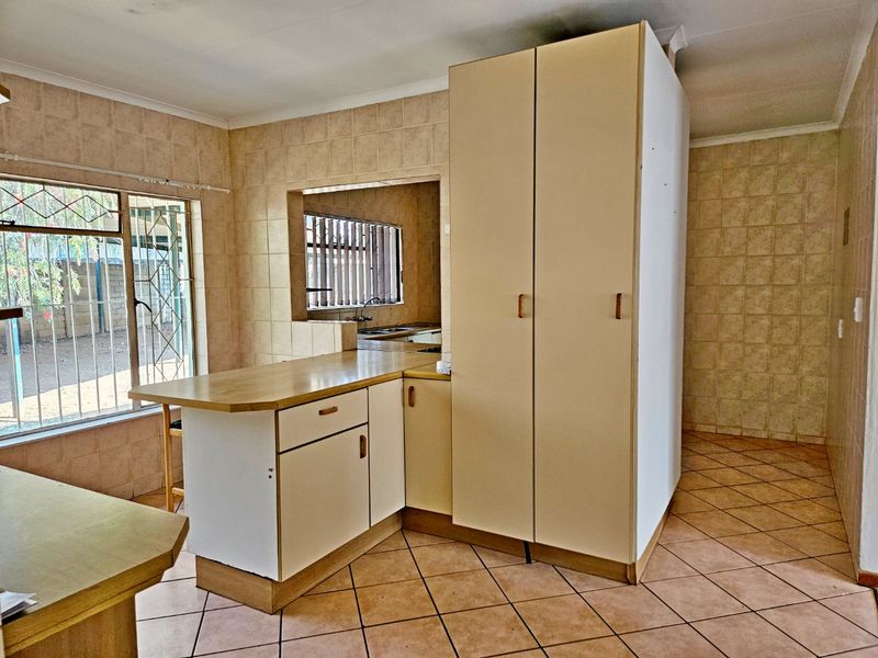A dated kitchen featuring tiled walls and flooring, built-in cabinetry, and a breakfast bar, offering a functional layout ready for modernization.