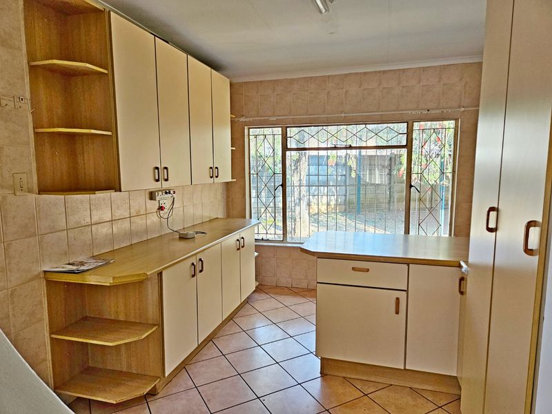 A functional kitchen featuring laminate countertops, built-in cabinetry, and tiled flooring, offering a clean, blank canvas for potential modern updates.