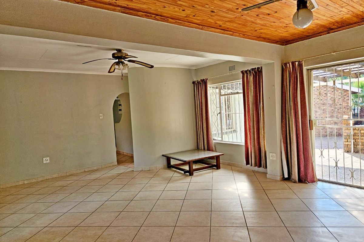 Spacious living area featuring tiled flooring, a timber ceiling, ceiling fans, and direct access to the outdoor area through a security gate.