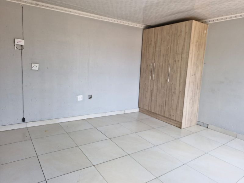 A bedroom featuring tiled flooring, ceiling cornice, and a built-in wooden wardrobe, requiring minor cosmetic repairs to walls and electrical fittings.