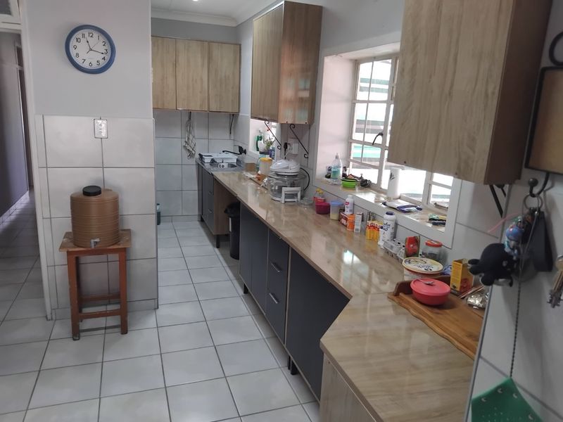 A functional kitchen featuring built-in cabinetry, laminate countertops, tiled flooring, and a tiled backsplash, providing a practical workspace with natural light.