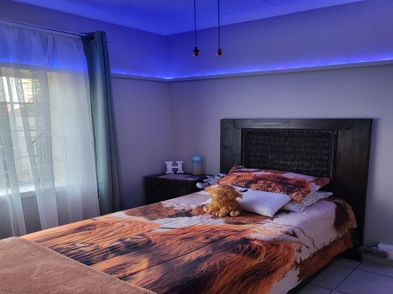 A bedroom featuring tiled flooring and integrated blue cove lighting, providing a modern ambient lighting effect.