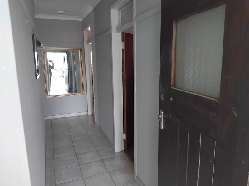 A functional hallway featuring tiled flooring, neutral wall finishes, and a traditional timber door with glass paneling.