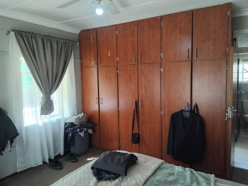 A bedroom featuring extensive floor-to-ceiling built-in wooden cabinetry and a ceiling fan, offering ample storage space.