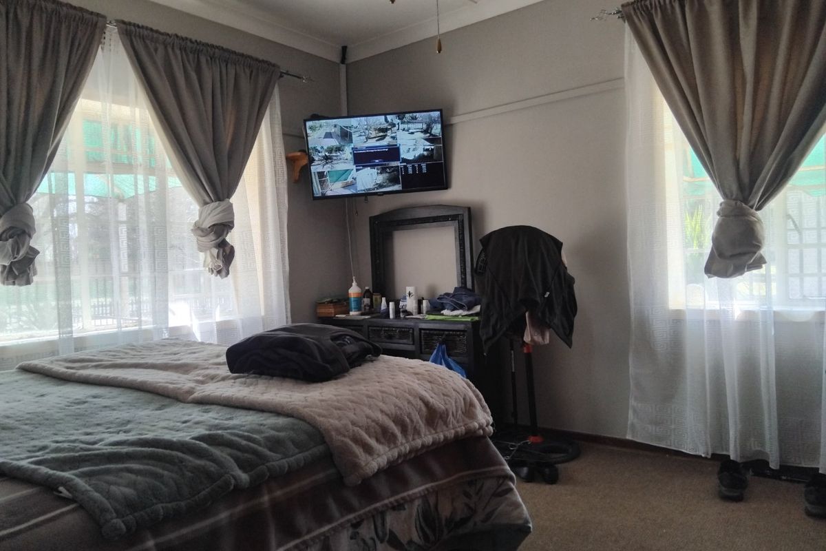 A standard bedroom featuring neutral wall tones, dual windows with curtain treatments, and carpeted flooring.