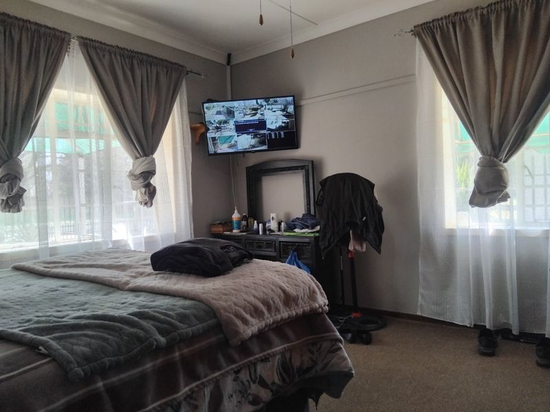 A standard bedroom featuring neutral wall tones, dual windows with curtain treatments, and carpeted flooring.