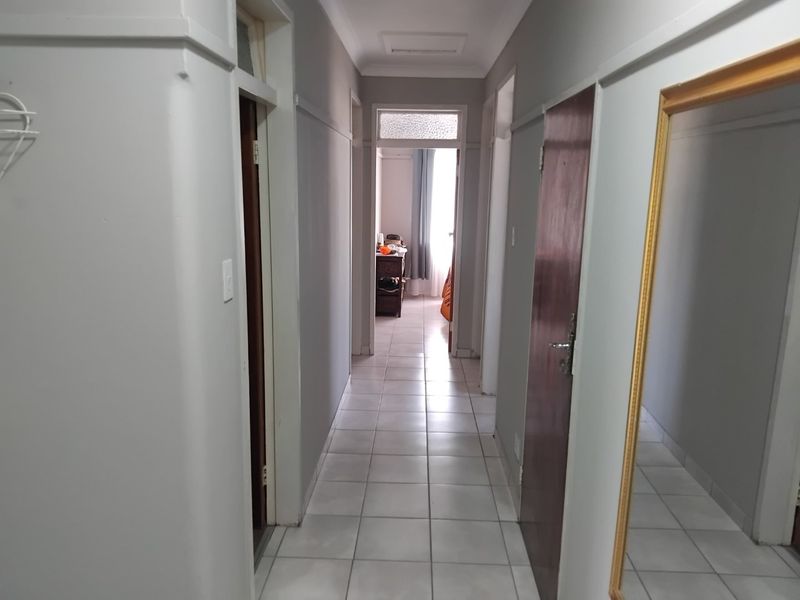 A clean and functional hallway featuring neutral wall tones, tiled flooring, and multiple internal door access points.