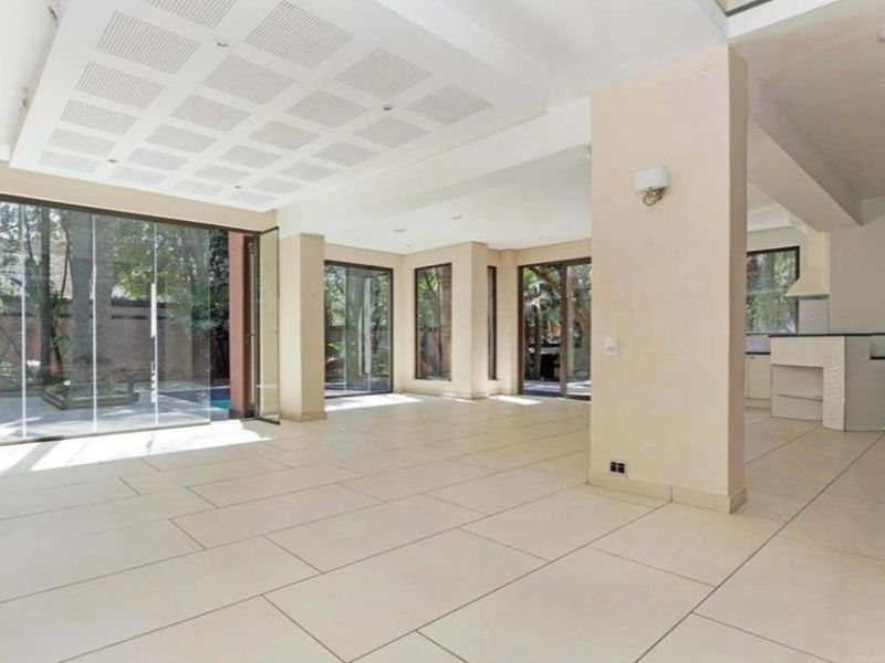 Spacious open-plan living and kitchen area featuring large sliding glass doors, modern tiled flooring, and a contemporary recessed ceiling design.