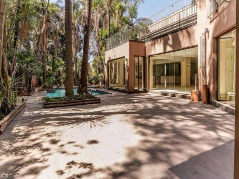 Rear exterior view featuring a paved patio area, swimming pool, and large glass sliding doors leading into the residence.