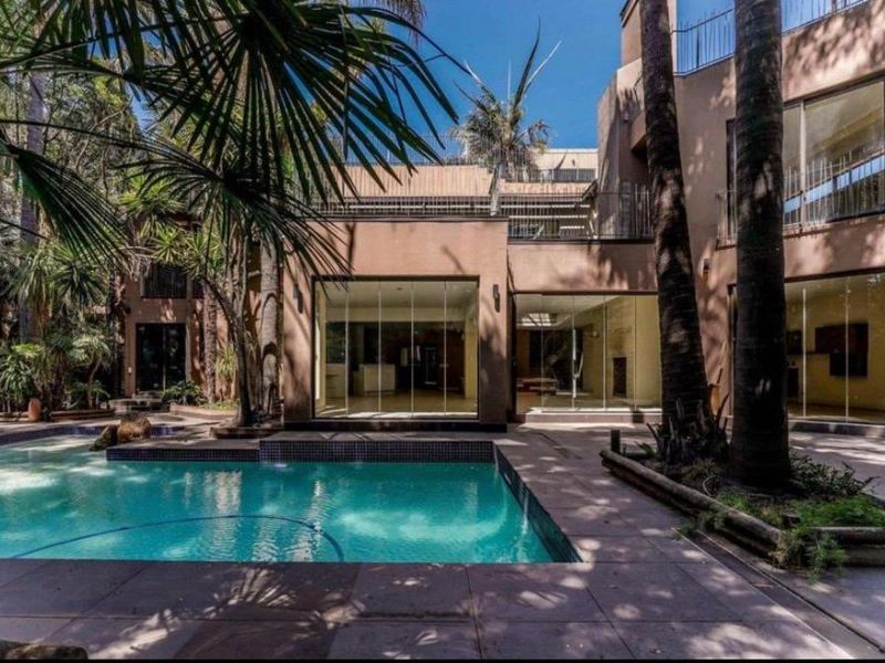 A modern rear exterior view featuring a swimming pool with tiled surround, large glass sliding doors, and a multi-level facade with balcony.