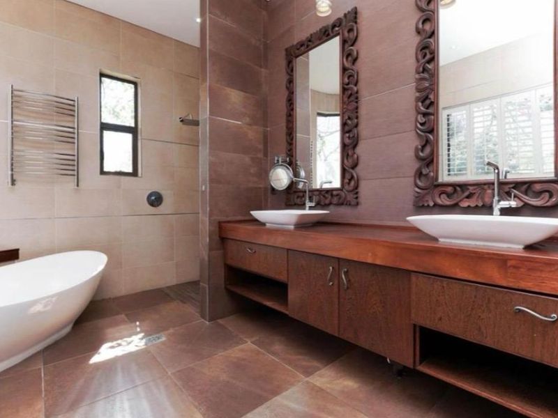 Modern bathroom featuring a double vanity with vessel sinks, a freestanding bathtub, and a walk-in shower with tiled finishes.