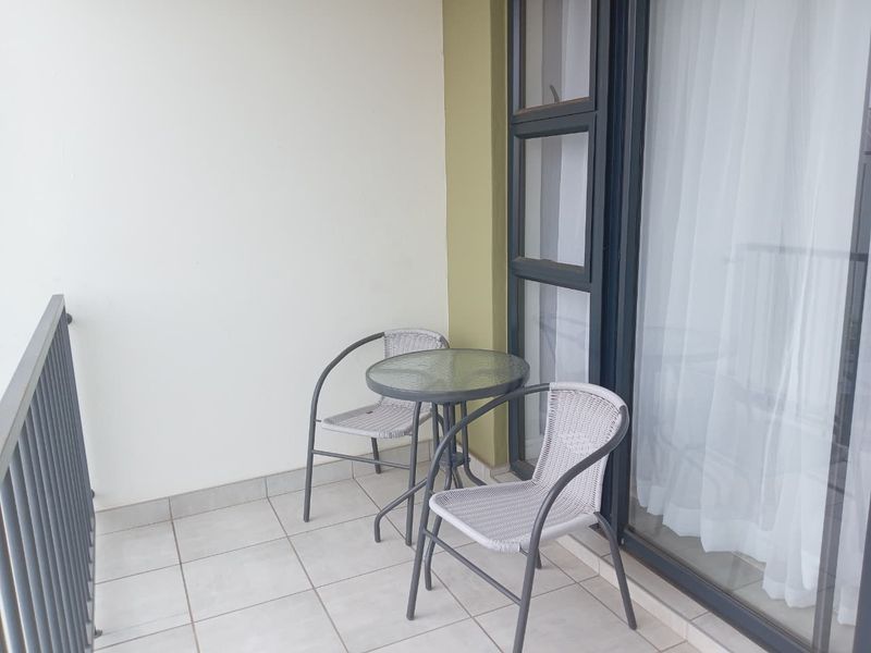 A private balcony featuring tiled flooring, a metal balustrade, and large sliding glass doors providing access to the interior living space.