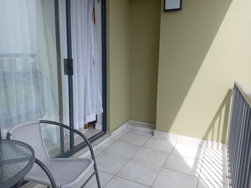 A private balcony featuring tiled flooring, a metal balustrade, and a sliding glass door providing access to the interior.