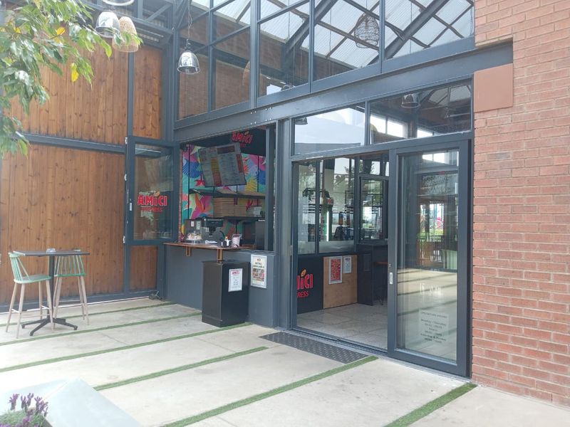 Modern commercial storefront featuring a steel and glass facade with brick accents and integrated outdoor patio space.