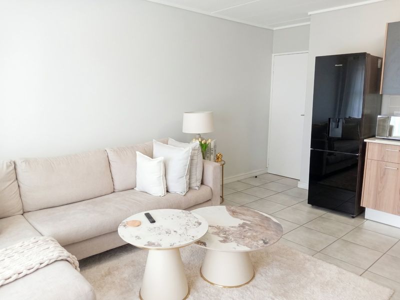 An open-plan living area featuring tiled flooring and a compact kitchen section with modern cabinetry.