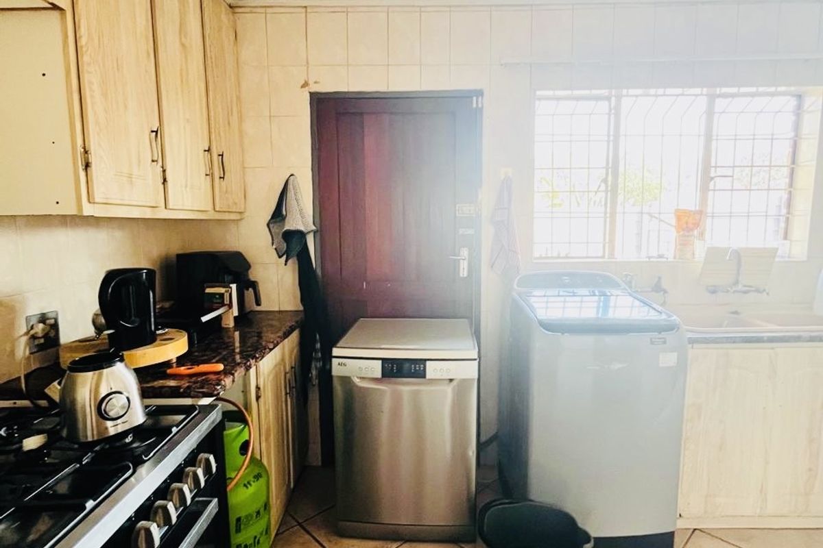 A functional kitchen featuring built-in cabinetry, a gas stove, and tiled finishes. The space shows signs of age and would benefit from cosmetic updates.