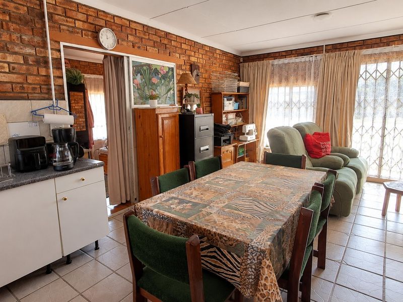 Open-plan living and dining area featuring exposed brick walls, tiled flooring, and a functional kitchen corner with direct access to the outdoor area.
