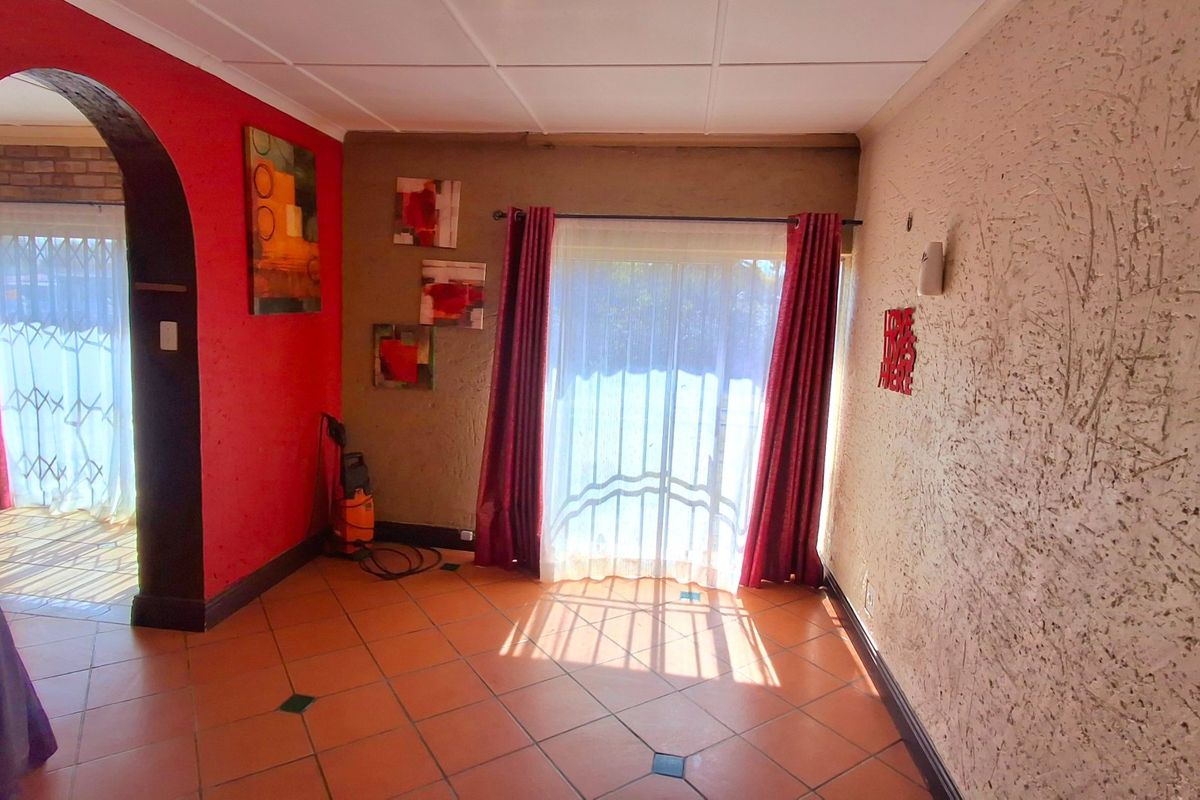 A living area featuring tiled flooring, a distinctive arched doorway, and a sliding glass door providing access to the exterior.