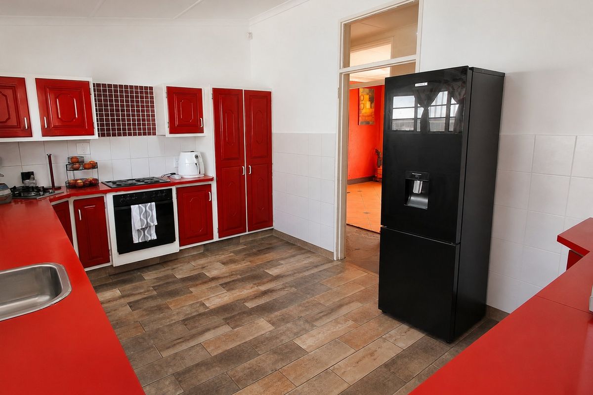 A functional kitchen featuring red cabinetry, laminate countertops, a built-in oven with gas hob, and tiled flooring.