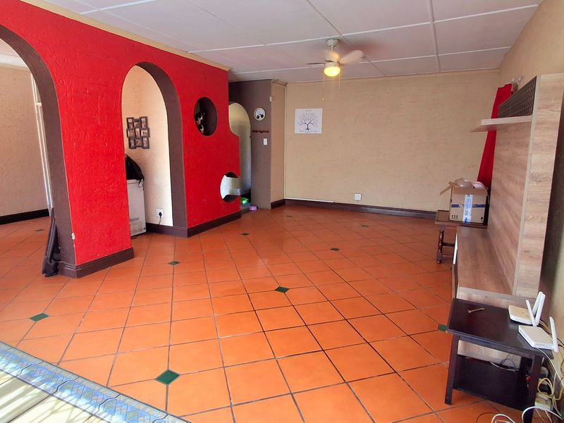 Spacious living area featuring distinctive arched doorways, tiled flooring, and a ceiling fan, offering a versatile layout for interior design updates.