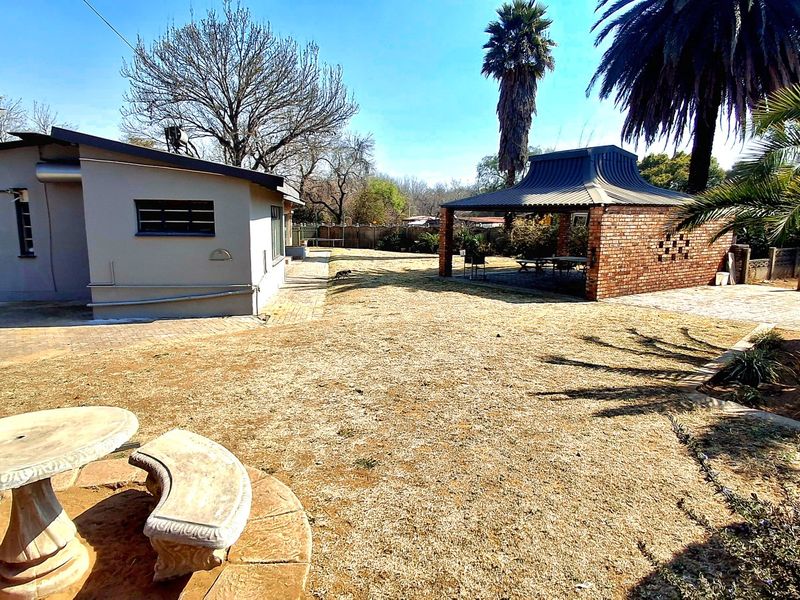 Spacious rear garden featuring a brick gazebo, paved patio area, and established landscaping, offering a functional outdoor entertainment space.