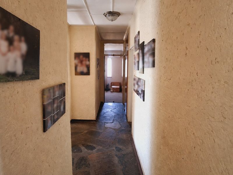A narrow hallway featuring rustic stone flooring and textured wall finishes, providing access to other areas of the home.