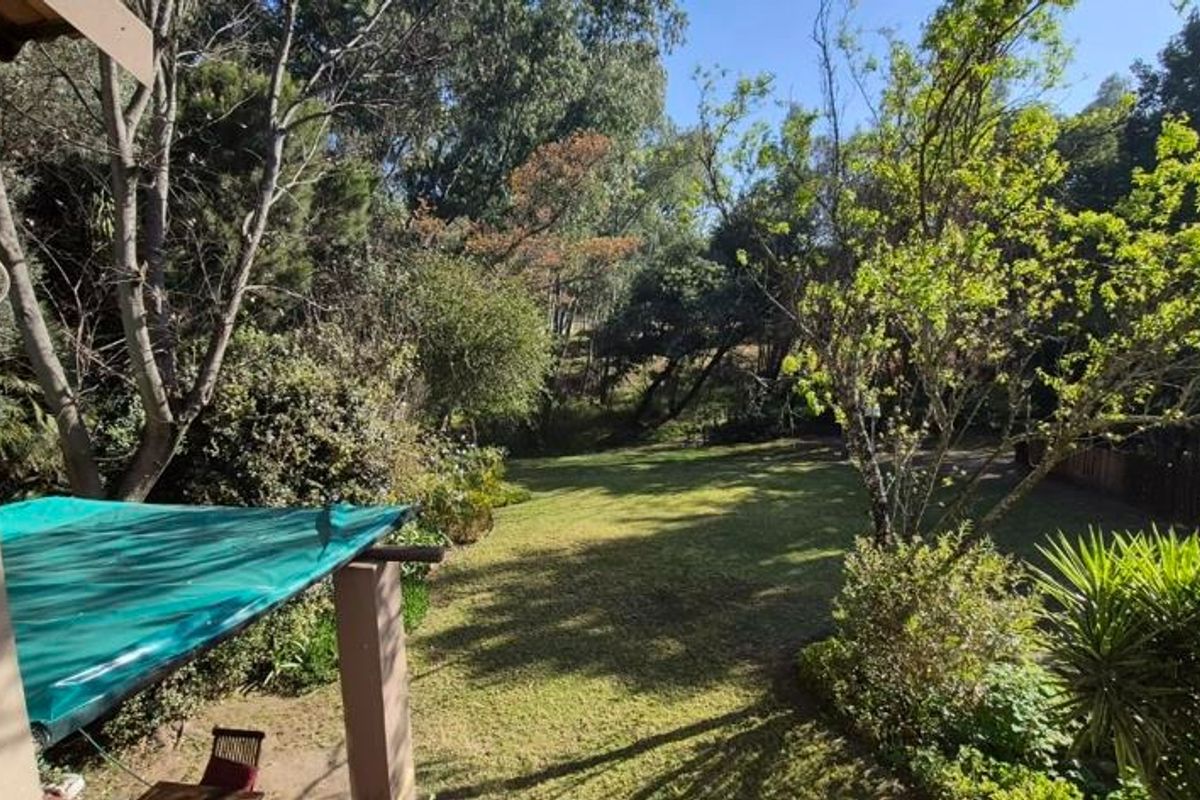 A view of the rear garden featuring a covered patio area and established trees, providing a private outdoor space.