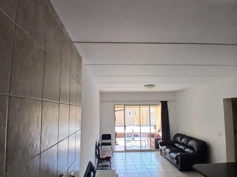 Open-plan living area featuring tiled flooring, a breakfast bar, and a sliding glass door leading to an outdoor balcony.