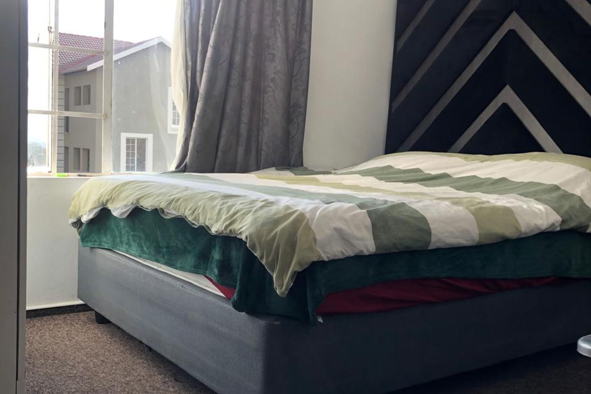 A bedroom featuring carpeted flooring and a large window providing natural light.