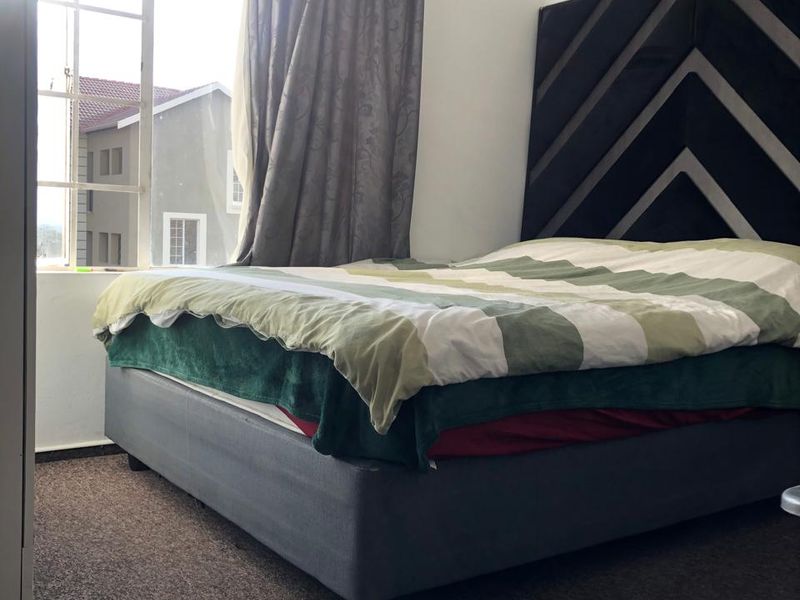 A bedroom featuring carpeted flooring and a large window providing natural light.