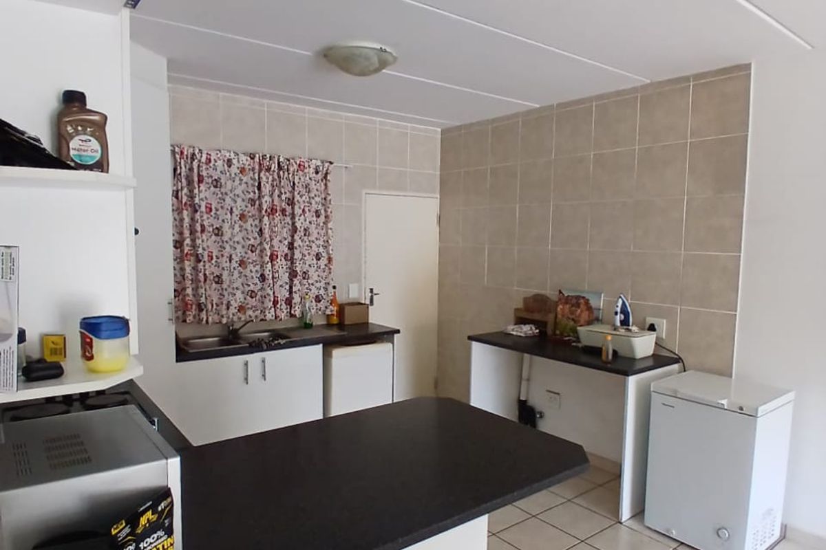 Functional kitchen area featuring tiled flooring, neutral wall tiles, built-in cabinetry, and laminate countertops with a breakfast bar extension.